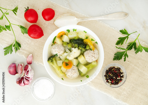 bowl of soup, a cup of broth and vegetables, meatballs made of turkey and chicken, top view, long width banner