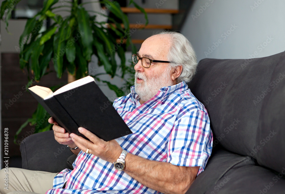 Retired man reading a book in his home Retired man reading a book in his home