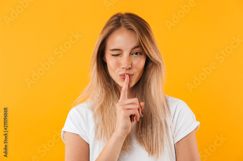 Portrait of a pretty young blonde girl showing silence gesture photo
