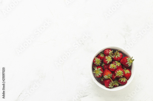White plate with strawberries on a light stone background. Flat lay, Top view