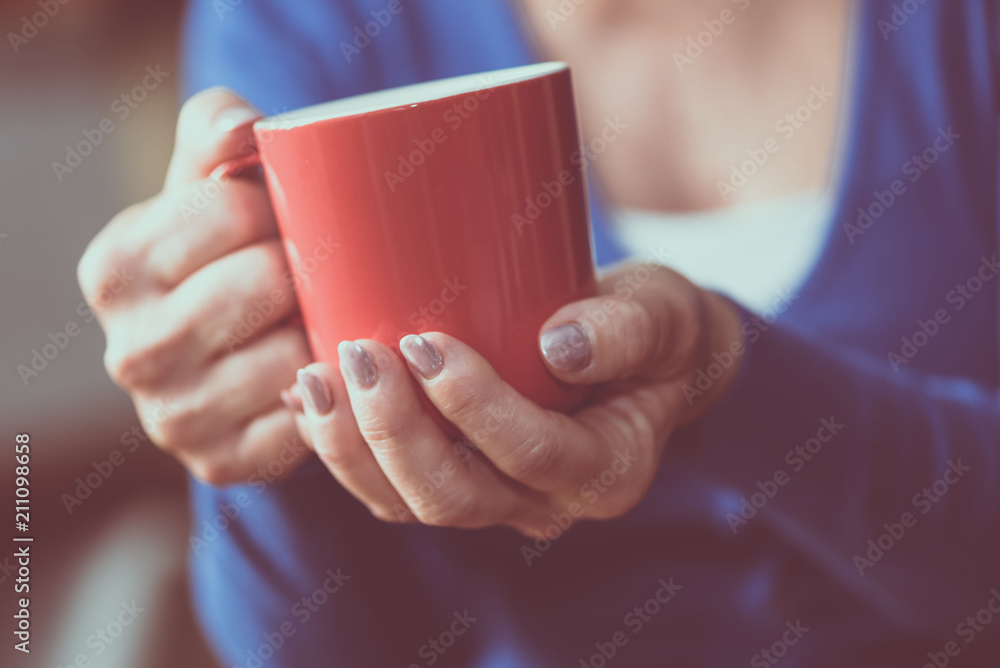 Woman's hands holding a mug of hot beverage Woman's hands holding a mug of hot beverage