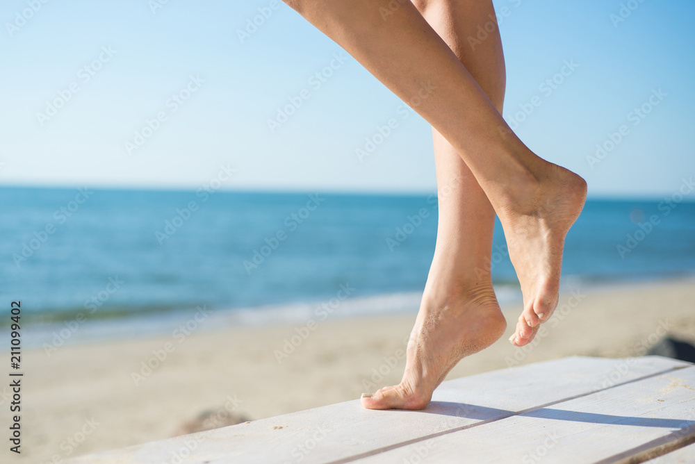 Woman's legs on the ocean or sea background, closeup Woman's legs on the ocean or sea background, closeup