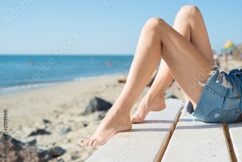 Woman's legs on the ocean or sea background, closeup