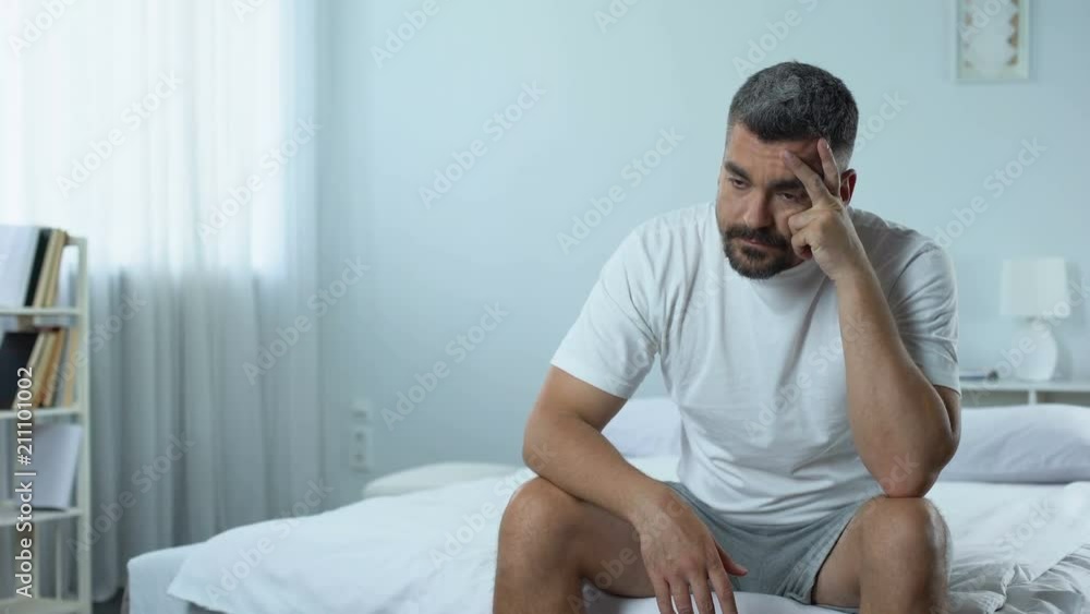 Sad unemployed man sitting in bedroom, thinking about plans for future depressed Sad unemployed man sitting in bedroom, thinking about plans for future depressed