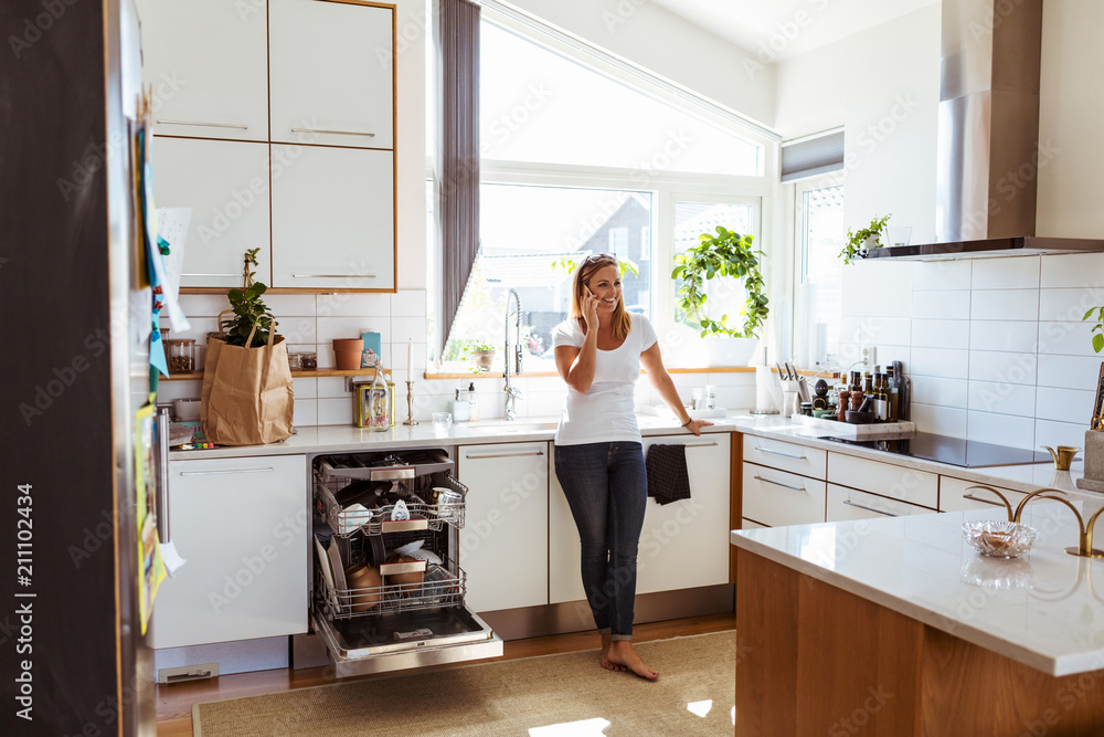 Woman standing in kitchen and talking on phone Woman standing in kitchen and talking on phone