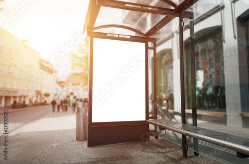 Bus stop billboard mockup. Sun light and street in background.