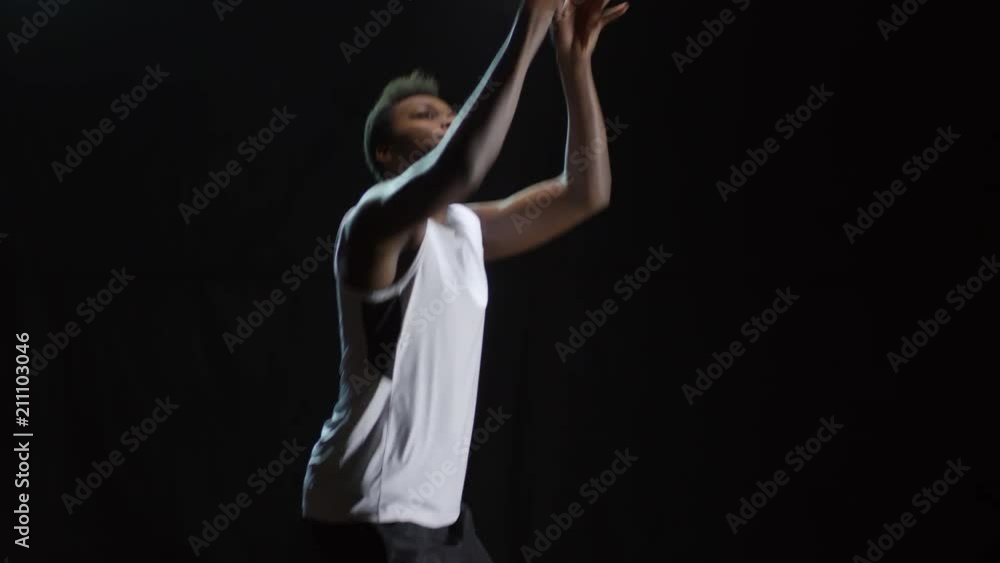 Studio shot of black male athlete catching basketball, then dribbling and shooting it; isolated on dark background Studio shot of black male athlete catching basketball, then dribbling and shooting it; isolated on dark background