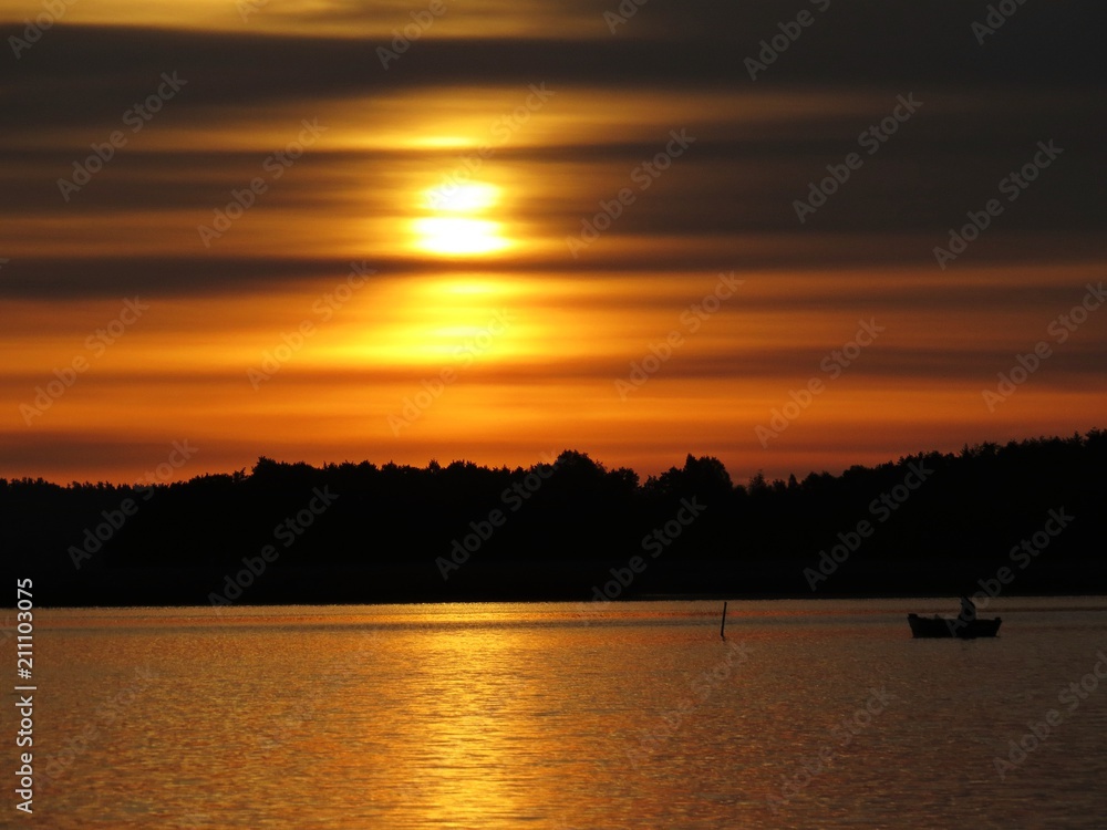 Sunset Over Beautiful Lake with Boat Silhouette and Cloudy Sky in background