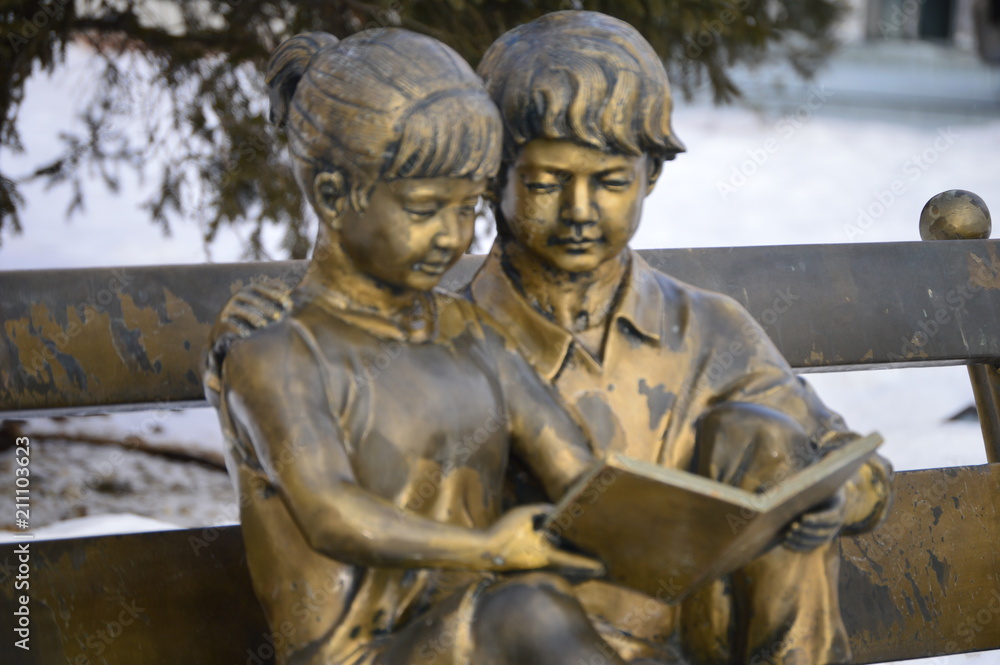 Boy and girl with the book , read and sit on the bench.