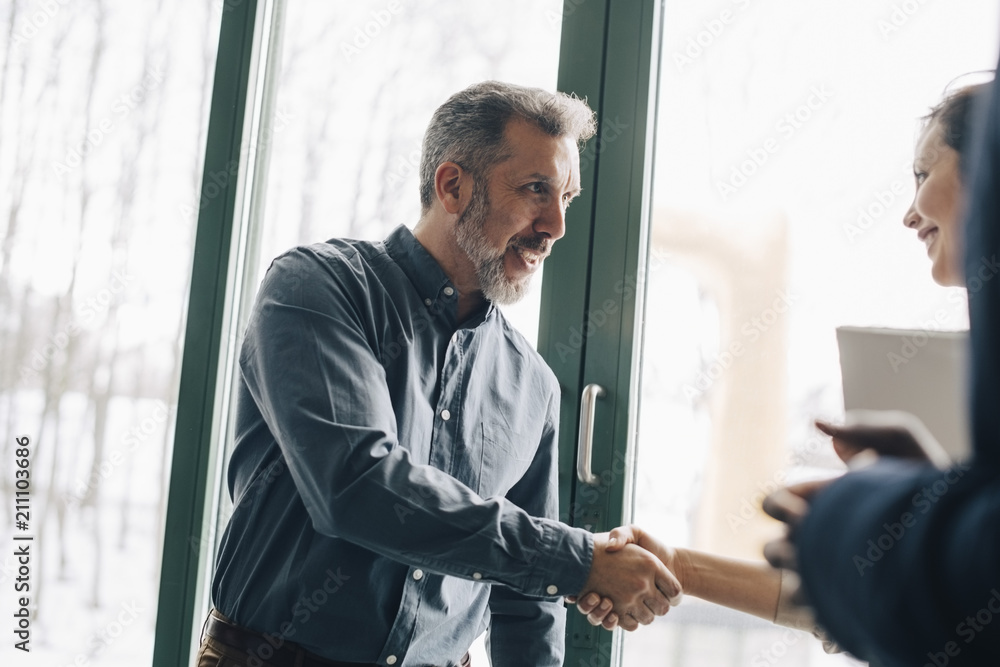 Mature businessman greeting female coworker in meeting at office Mature businessman greeting female coworker in meeting at office