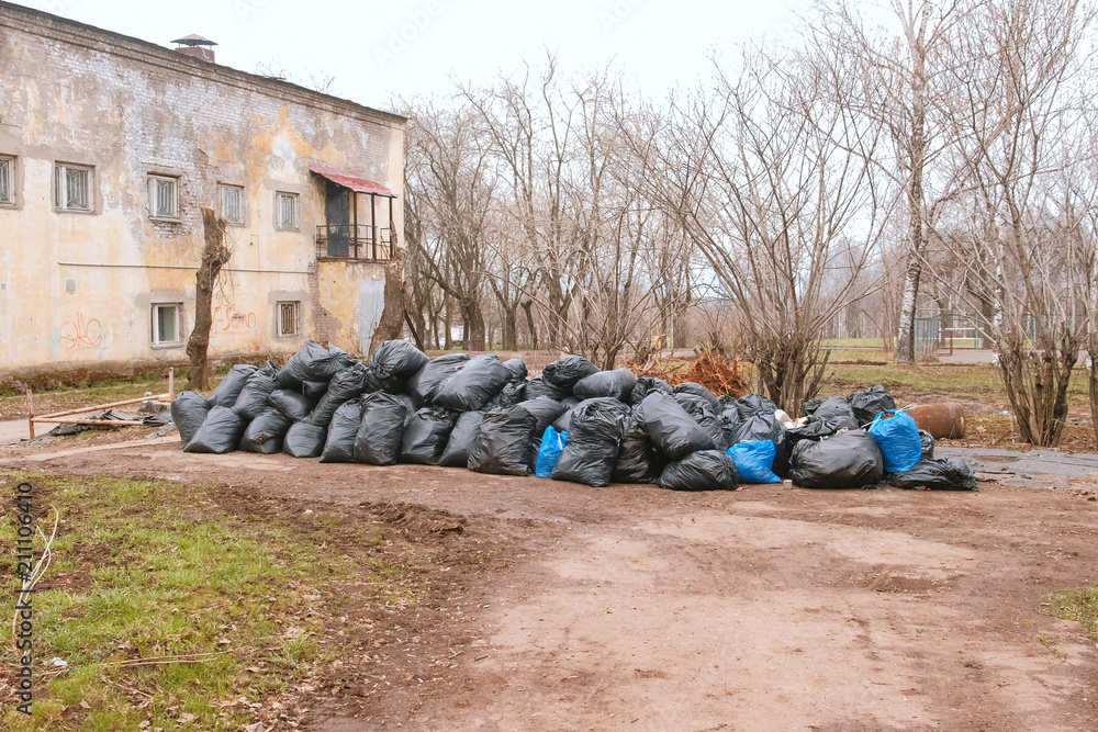 Black trash bags piled up In the city against house. Black trash bags piled up In the city against house.
