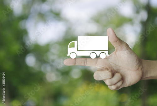 Truck flat icon on finger over blur green tree background, Business transportation service concept