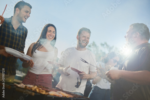 Photography Group of people standing around grill, chatting, drinking and eating