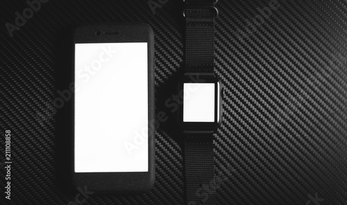 Black smartphone and Black Smartwatch on carbon fiber desk