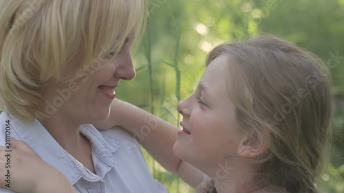 Cheerful blonde mother and child looking at each other, touching noses, smiling photo