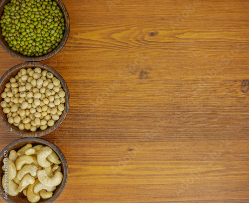 Flat lay top view assorted beans included cashews green beans and soybeans on wooden table with copy space