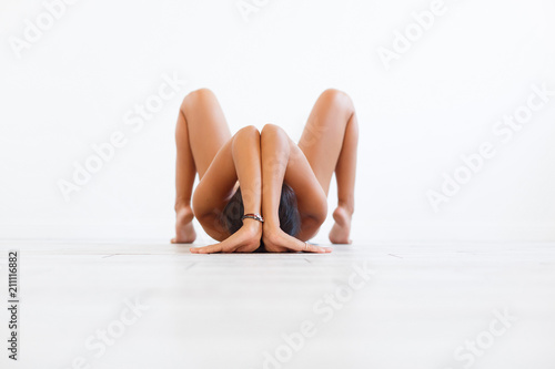 Beautiful young unidentified woman with sporty tight body doing an exercise on yoga on a white background. Copyspace