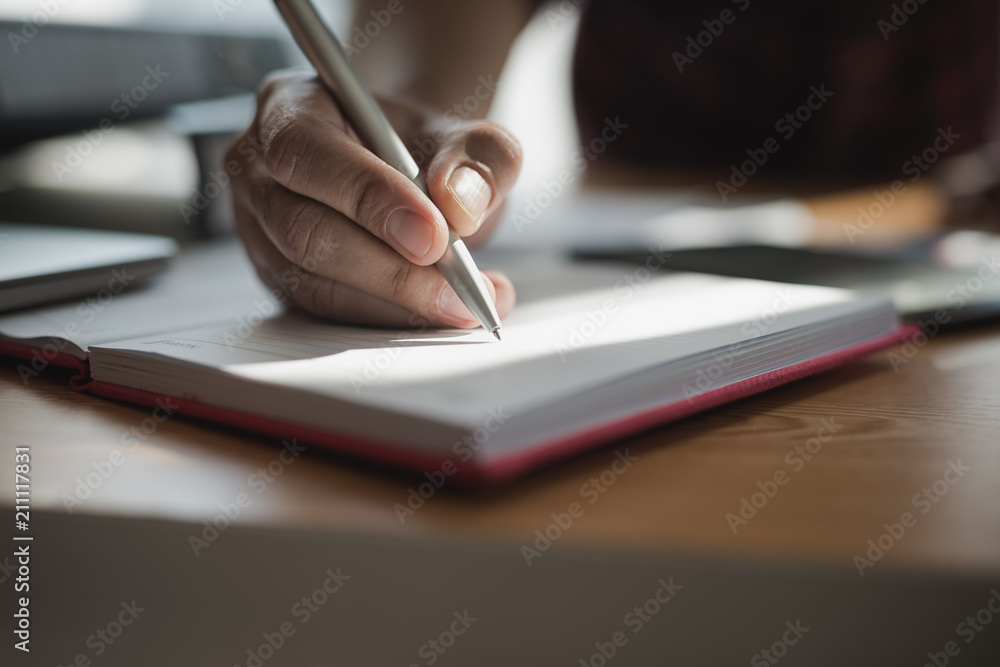 Hand of businessmen holding pen while writing notes in the book during the meeting.. Hand of businessmen holding pen while writing notes in the book during the meeting..