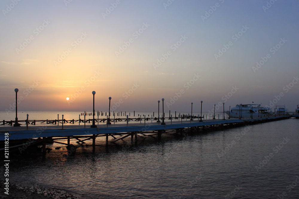 Sunrise on the sea. Pier stretching into infinity. Morning sun rays. Red sea, Safaga, Egypt.