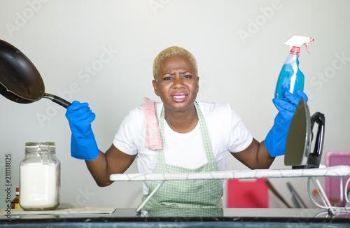 young attractive stressed and upset back afro American woman in washing rubber gloves cleaning home kitchen tired and overworked in domestic work