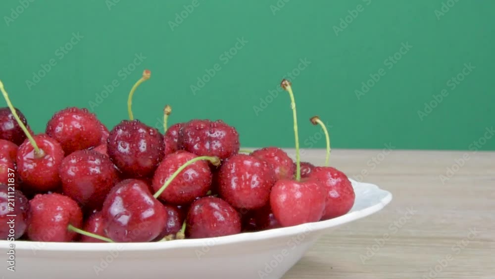 Ripe red cherries. Drops of water on cherries. Green background. Slider shot. Ripe red cherries. Drops of water on cherries. Green background. Slider shot.