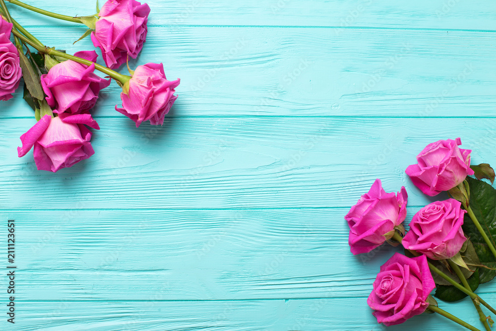 Obraz premium Granica od różowych róż kwitnie na cyraneczki koloru drewnianym tle. Kwiatowa makieta. Widok z góry. Miejsce na tekst.