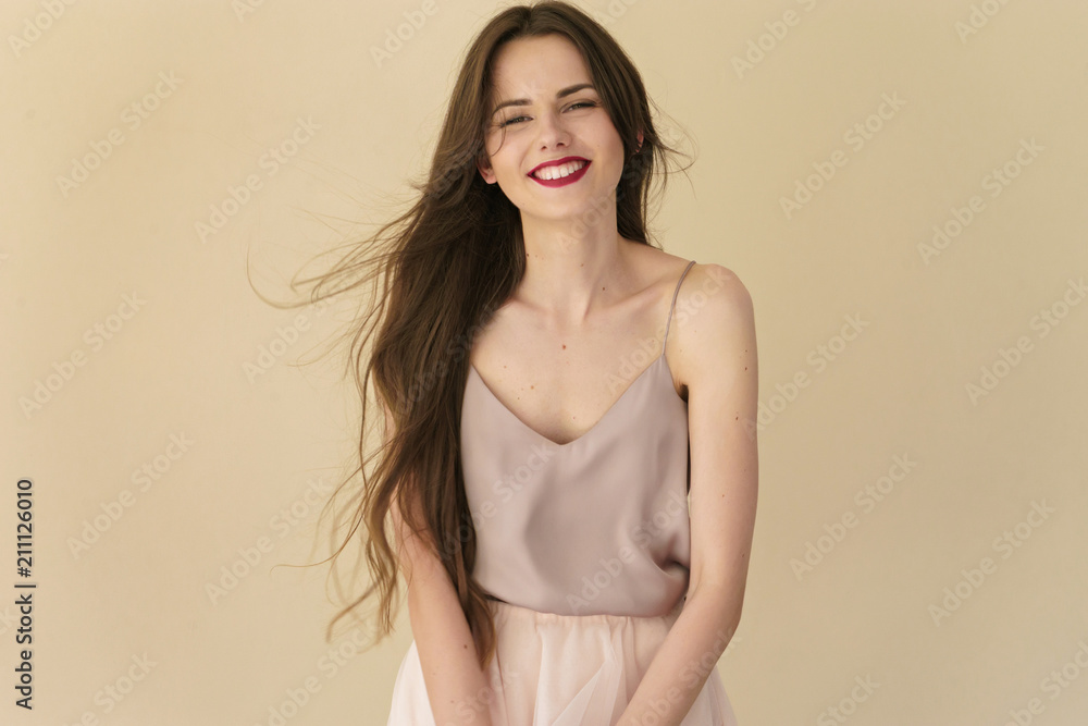 Fototapeta premium portrait of beautiful smiling young woman on beige background