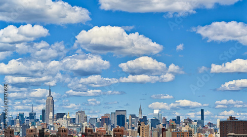 View of the Manhattan skyline (New York City) in daylight with beautiful low clouds in the clear sky. Skyscapers and buildings in the finance district of an American city