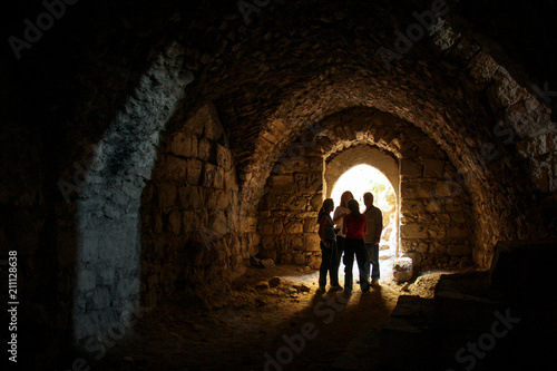 KERAK, JORDAN - Nov 2009: A small group of tourists stand in a dark chamber, silhouetted by glowing sunlight through an archway window inside the ancient crusader castle at Karak near Amman in Jordan