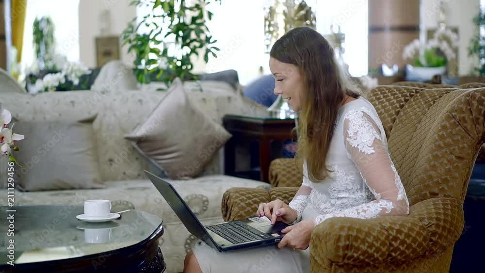 young and pretty woman watching a movie on a laptop, a lady is sitting in a hotel lobby and drinking coffee young and pretty woman watching a movie on a laptop, a lady is sitting in a hotel lobby and drinking coffee