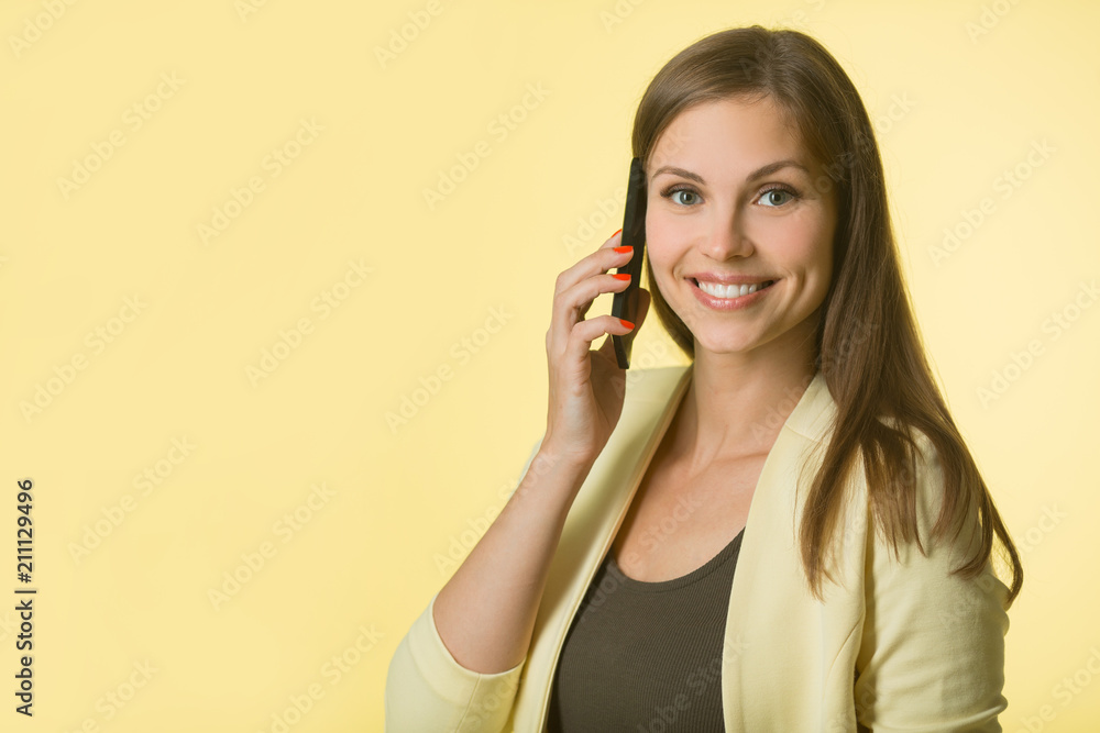 beautiful young girl in a yellow jacket on a yellow background with a phone in her hand beautiful young girl in a yellow jacket on a yellow background with a phone in her hand