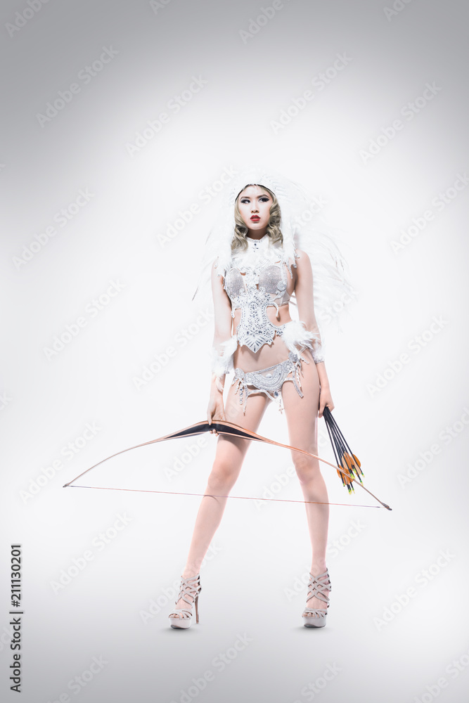 Asiatisch wirkende frau mit federschmuck und einem glamouroutfit als Showgirl mit Pfeil und Bogen Asiatisch wirkende frau mit federschmuck und einem glamouroutfit als Showgirl mit Pfeil und Bogen