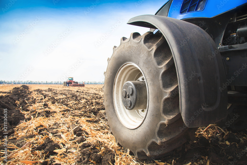 Fototapeta premium A wheel from a tractor working in the field close up. The concept of agriculture.