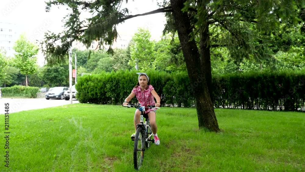 Pretty girl rides a bicycle in the park. Slow motion footage Pretty girl rides a bicycle in the park. Slow motion footage