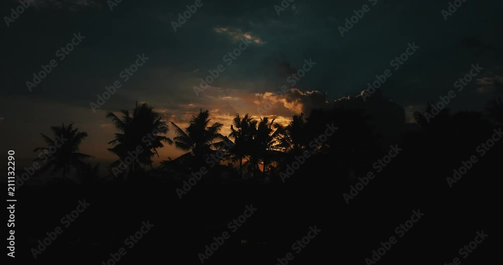Aerial drone view of amazing cloudy sunset with with silhouettes of tropical palm trees in Bali, Indonesia