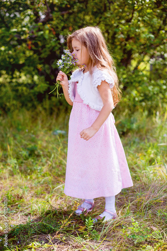 in summer  a little girl in bright clothes holds wild flowers