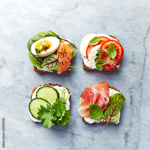 Healthy open sandwiches with vegetables, salmon, ham, herbs and soft cheese. Flat lay. Healthy diet concept. 