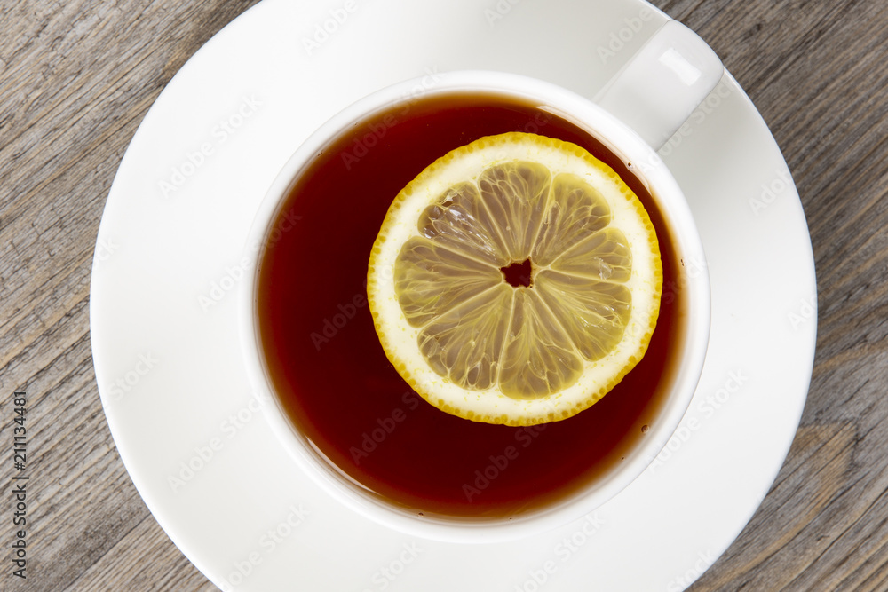 Tea with lemon in a white mug on a wooden table. Top view. Tea with lemon in a white mug on a wooden table. Top view.