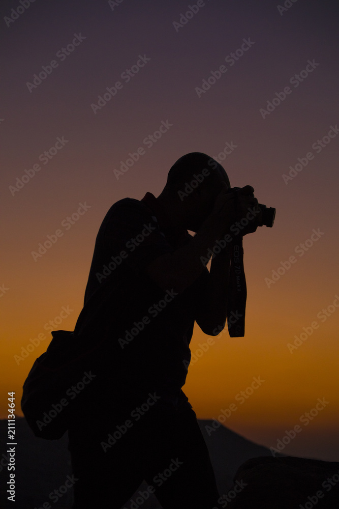 silhouette of a photographer with camera with sunset and sky in background