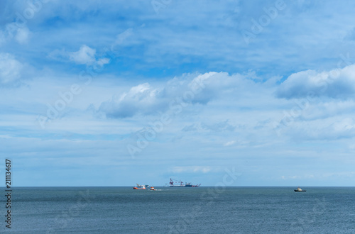 Ships in the sea on the horizon. Oil drilling in the sea. Calm and cloudy sky. © SeagullNady