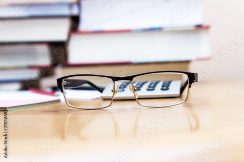 glasses on the background of books and a calculator.