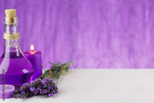 Spa products, aroma candle and lavender flowers on a wooden background © liptakrobi