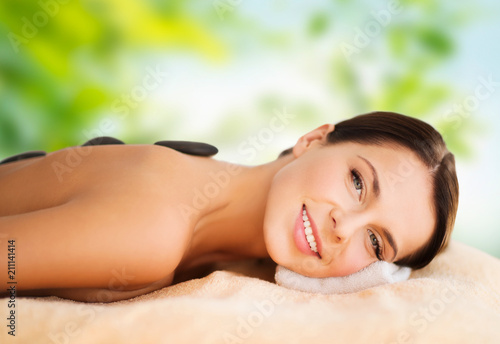 wellness  spa and beauty concept - beautiful woman having hot stone therapy over green natural background