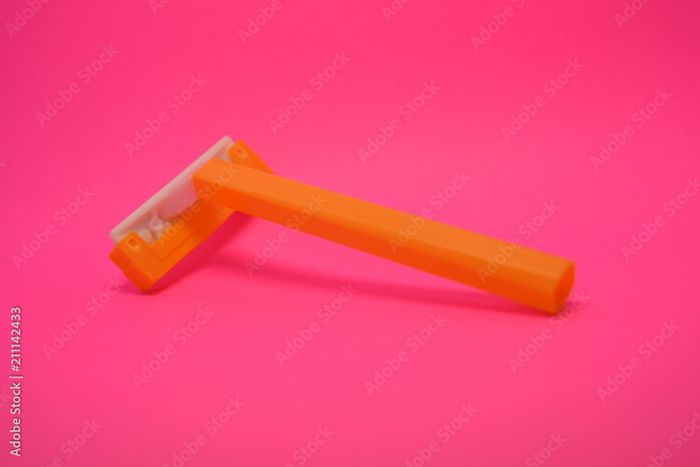 On a bright colorful pink paper background is located and placed a yellow disposable shaving machine On a bright colorful pink paper background is located and placed a yellow disposable shaving machine