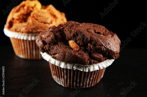 Chocolate muffin and nut muffin, homemade bakery on dark background.
