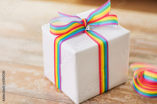 homosexual and lgbt concept - close up of gift box with gay pride awareness ribbon on wooden table at home