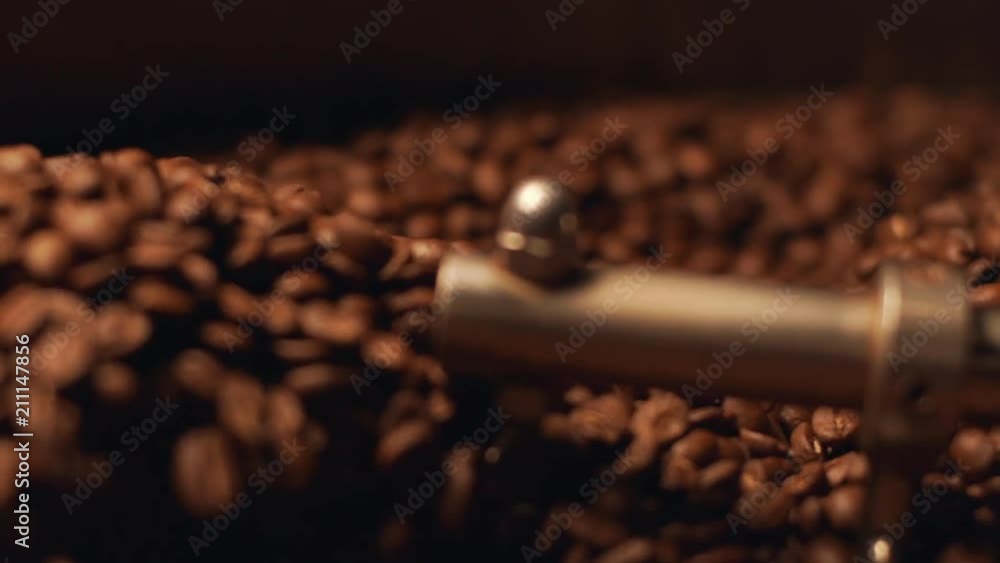 Closeup view of aromatic brown coffee beans rotating in special cooler after roasting, in slow motion