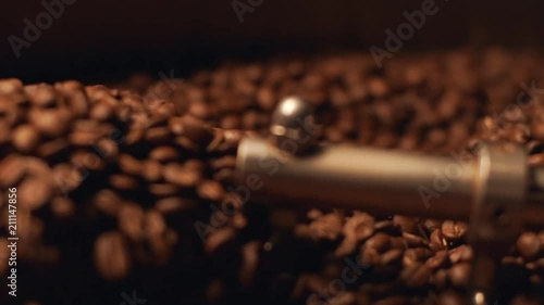 Closeup view of aromatic brown coffee beans rotating in special cooler after roasting, in slow motion
