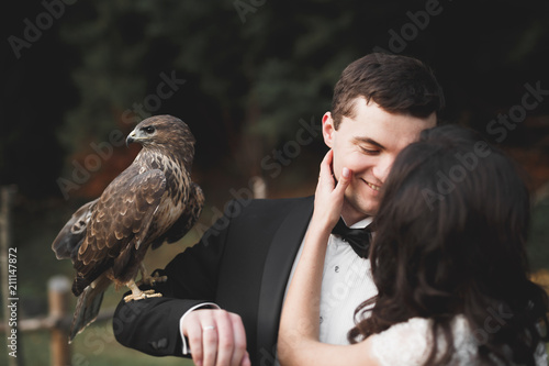 Stylish couple of happy newlyweds walking in the park on their wedding day with bouquet