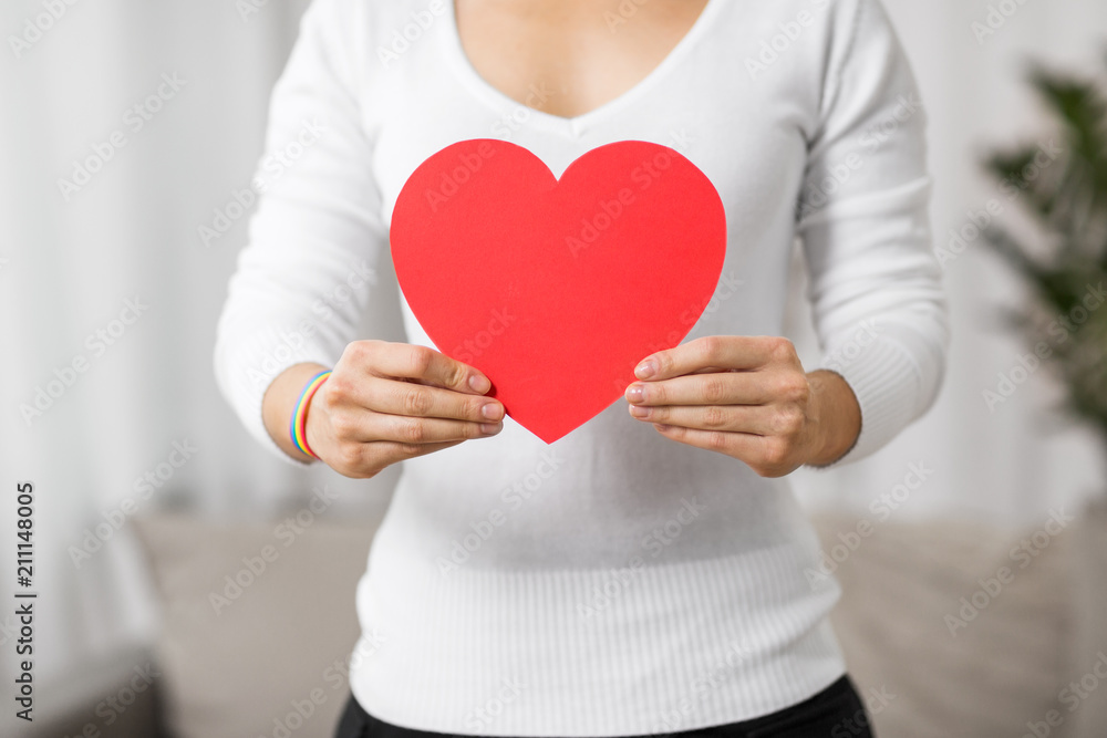 homosexual and lgbt concept - woman holding red heart shape and wearing gay pride awareness ribbon wristband homosexual and lgbt concept - woman holding red heart shape and wearing gay pride awareness ribbon wristband